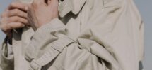 Närbild av en beige trenchcoat med bälte, slag och ärmdetaljer