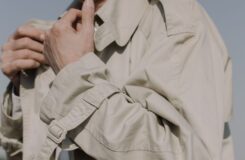 Närbild av en beige trenchcoat med bälte, slag och ärmdetaljer