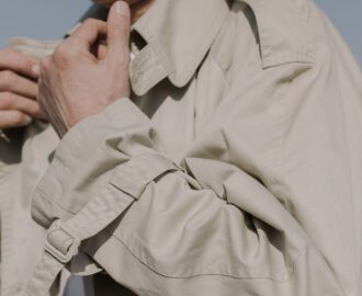Närbild av en beige trenchcoat med bälte, slag och ärmdetaljer
